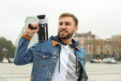 Photo of Young man with vintage video camera on city street