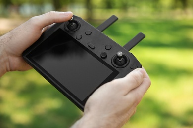 Man holding new modern drone controller outdoors, closeup of hands