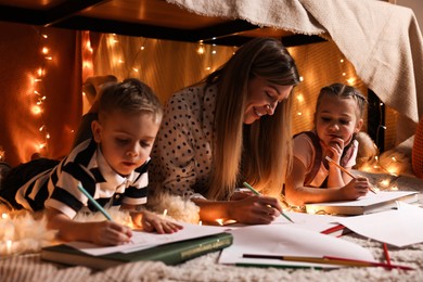 Mother and her children drawing in play tent at home