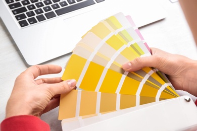 Photo of Woman with palette samples at white table, closeup