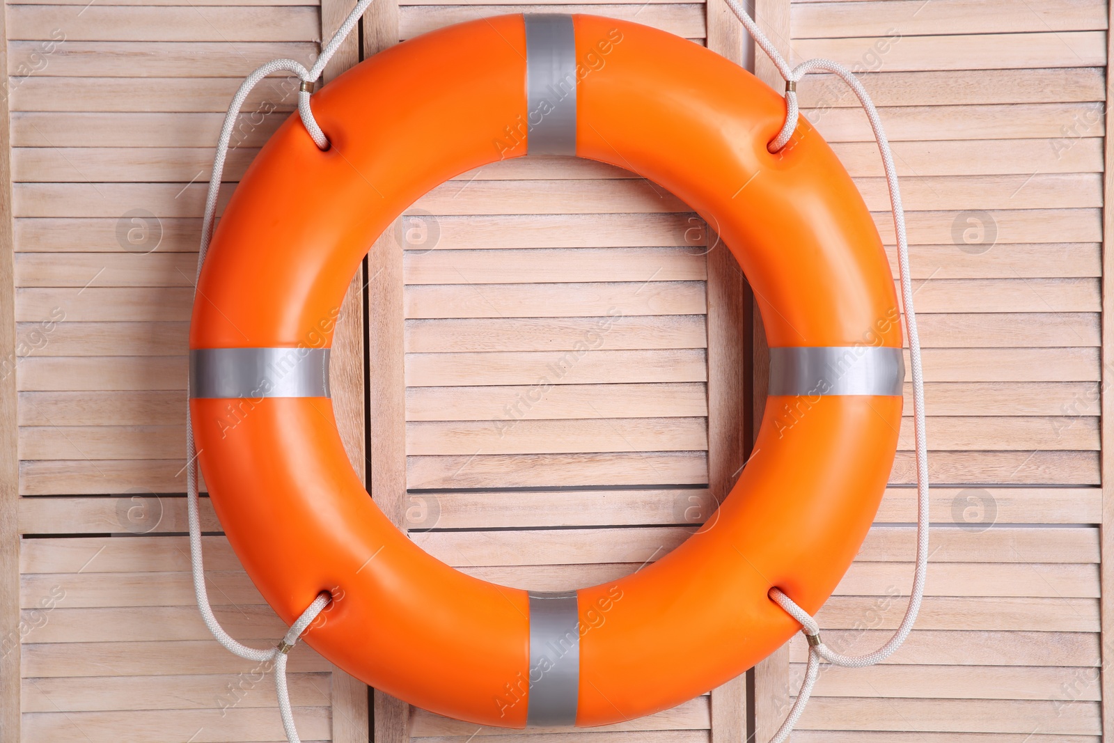 Photo of Orange lifebuoy on wooden background. Rescue equipment