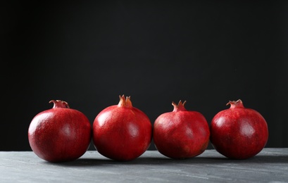 Ripe pomegranates on table against black background, space for text