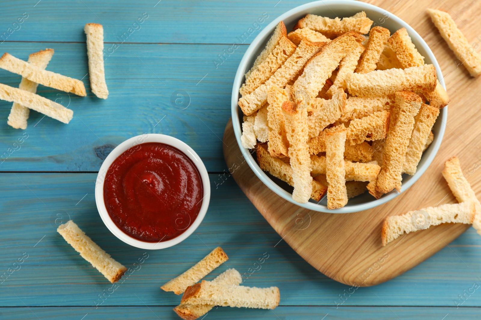 Photo of Delicious hard chucks with ketchup on light blue wooden table, flat lay