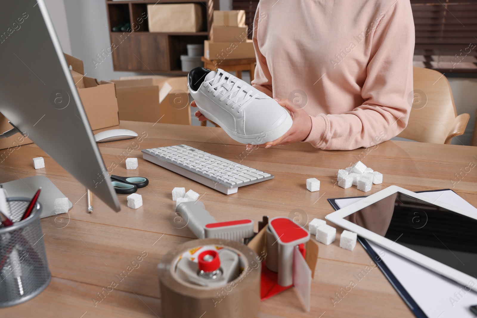 Photo of Shoes seller working at table in office, closeup. Online store