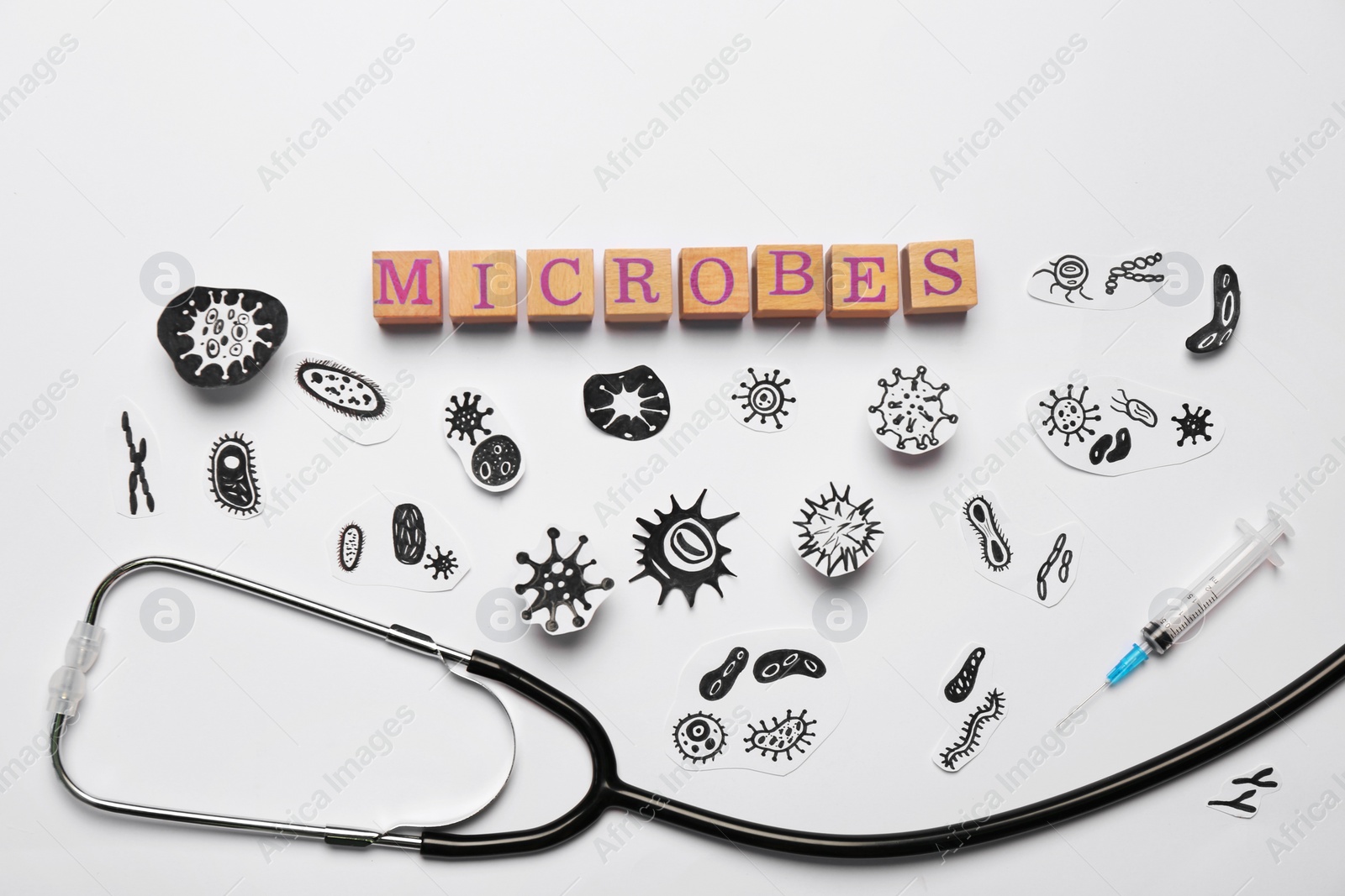 Photo of Word Microbes made with wooden cubes, pictures, syringe and stethoscope on white background, flat lay