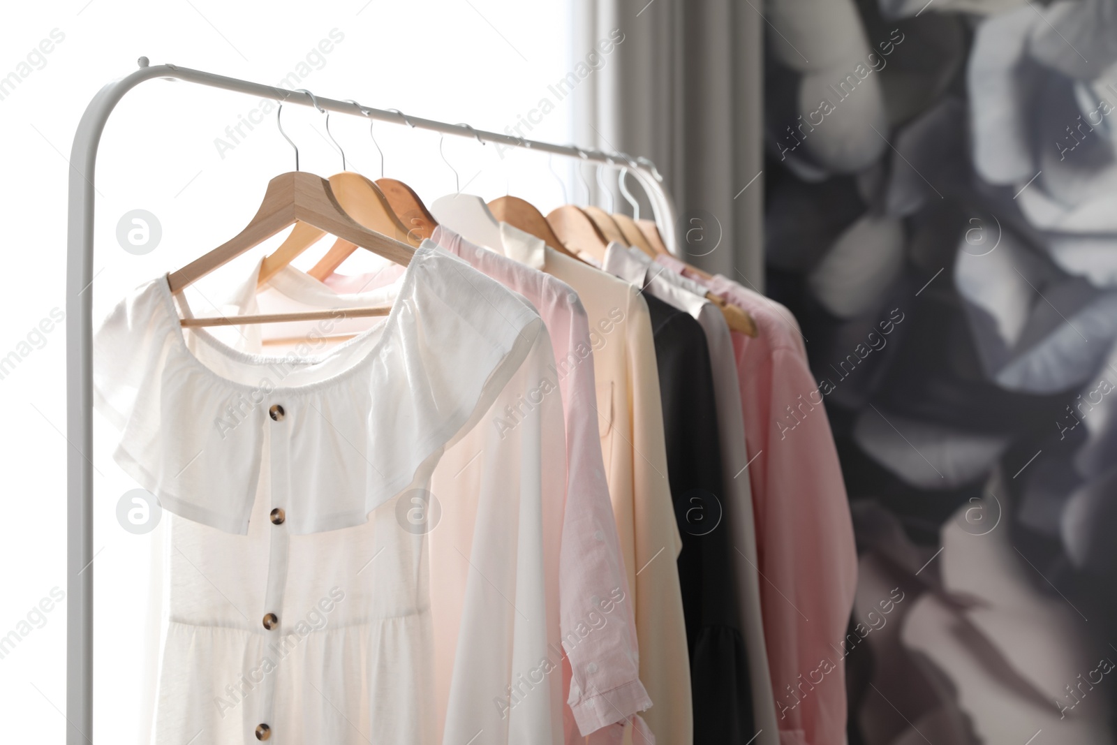 Photo of Rack with stylish women's clothes indoors. Interior design