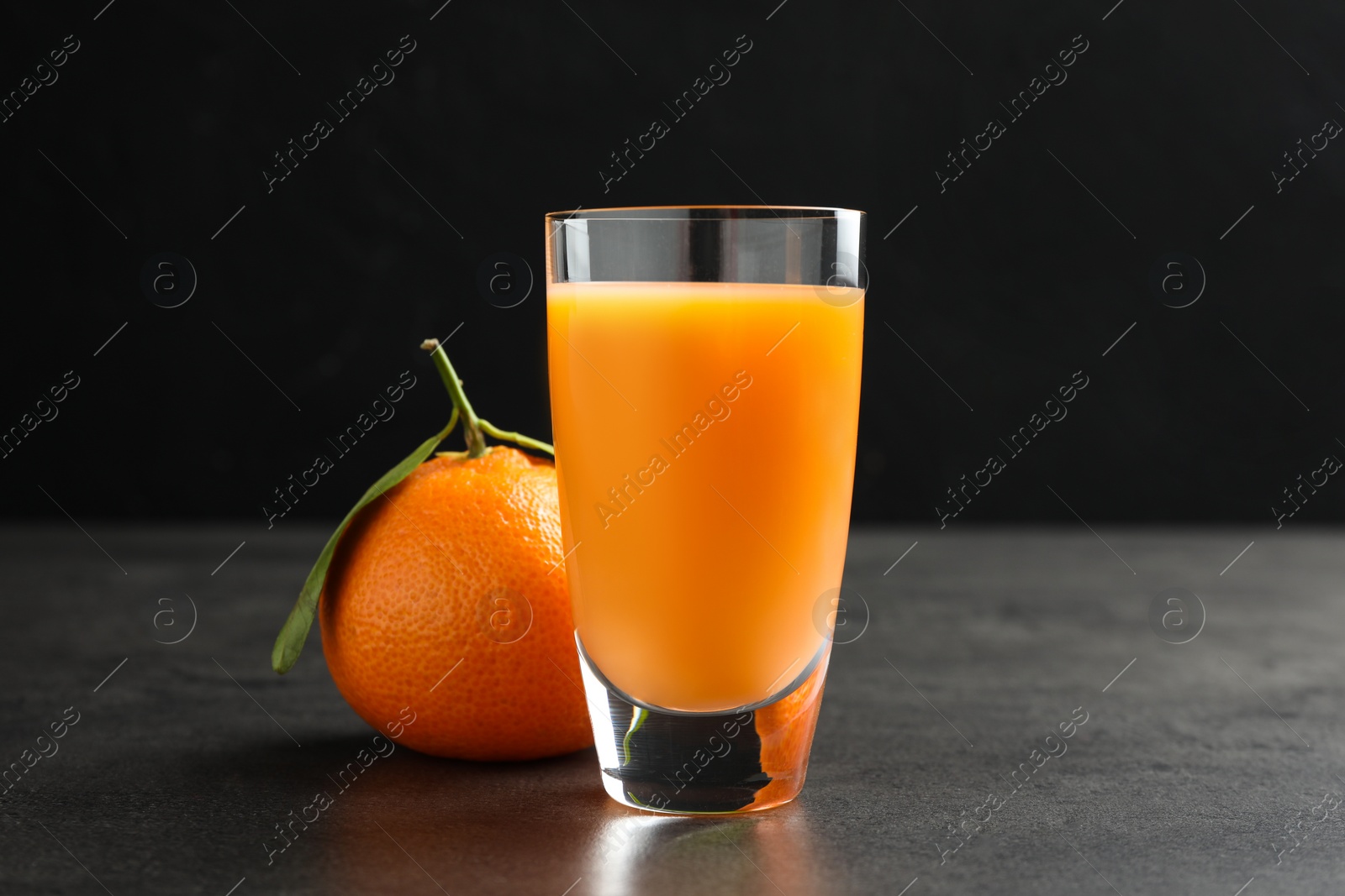 Photo of Delicious tangerine liqueur and fresh fruit on grey table