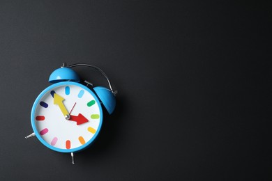 Alarm clock and space for text on black background, top view. School time