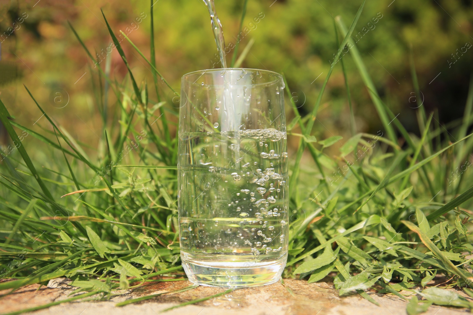 Photo of Pouring fresh water into glass on sunny day