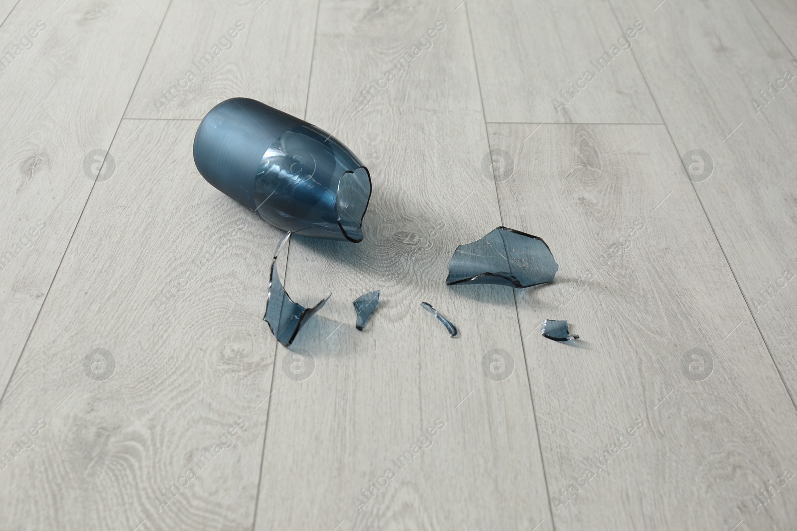 Photo of Broken blue glass vase on wooden floor