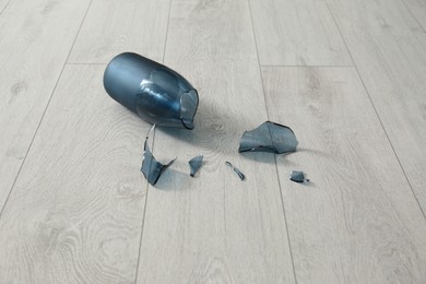 Broken blue glass vase on wooden floor