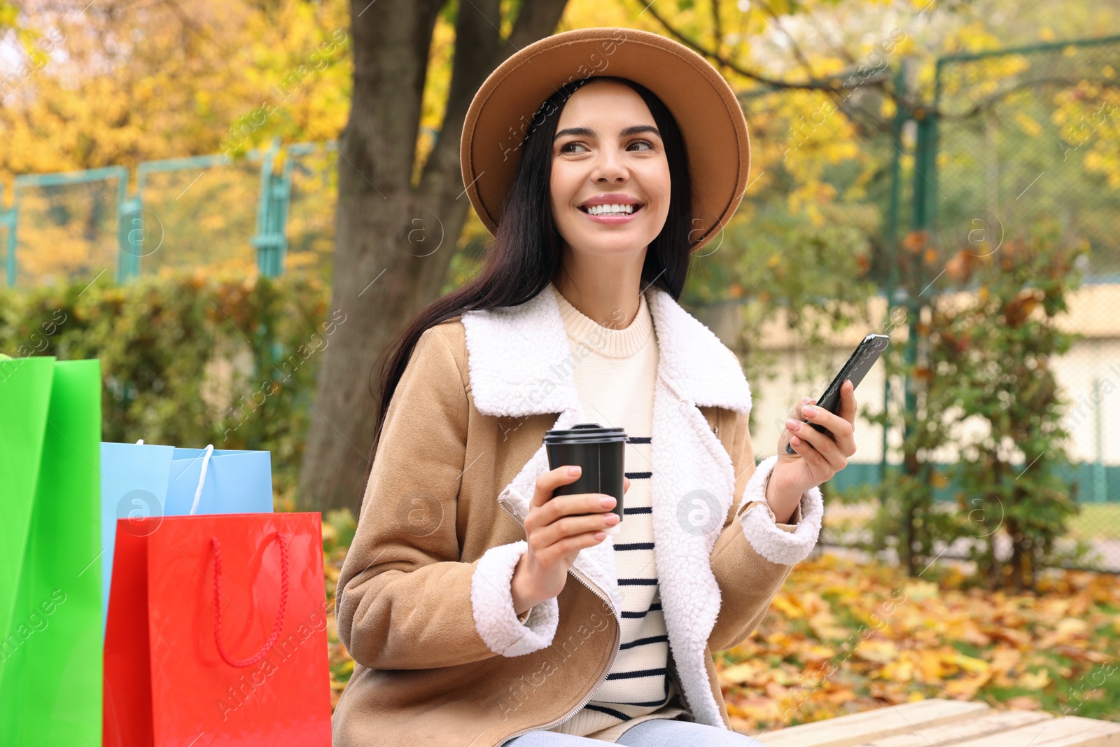 Photo of Special Promotion. Happy young woman with smartphone and cup of drink in park