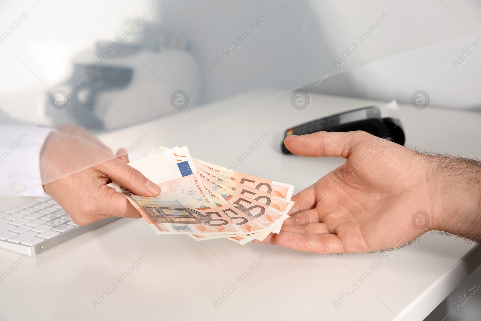 Photo of Man receiving money from teller at cash department window, closeup