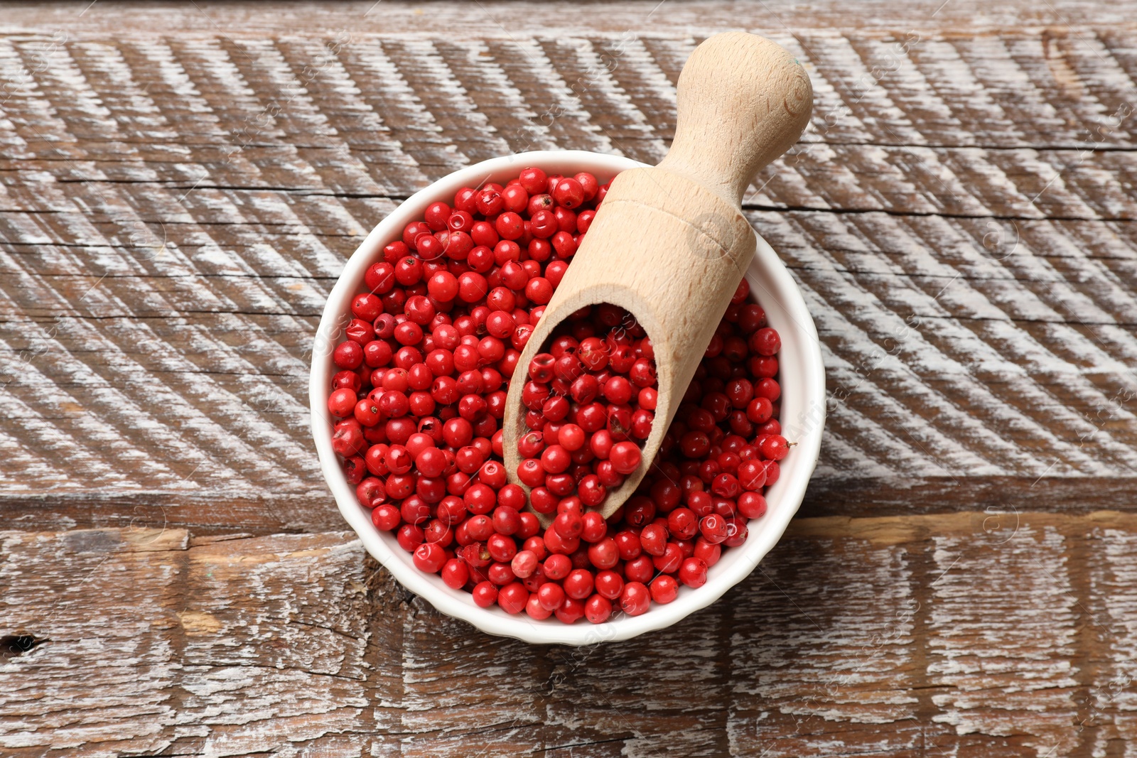 Photo of Aromatic spice. Red pepper in bowl and scoop on wooden table, top view