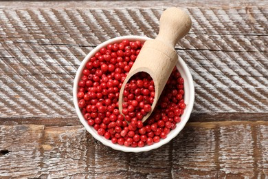 Aromatic spice. Red pepper in bowl and scoop on wooden table, top view