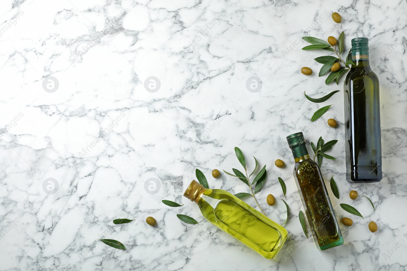 Photo of Flat lay composition with bottles of olive oil and space for text on marble background