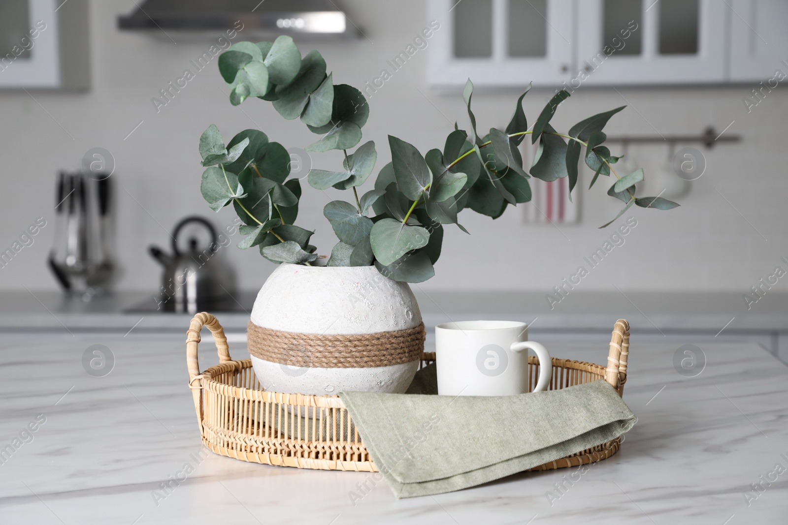 Photo of Vase with beautiful eucalyptus branches on white marble table in kitchen