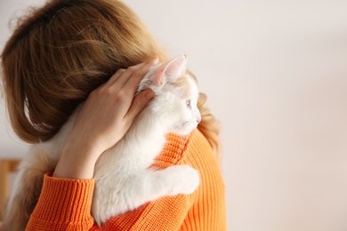 Photo of Woman with cute fluffy cat on beige background