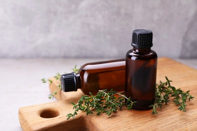 Photo of Wooden board with thyme essential oil on table, closeup
