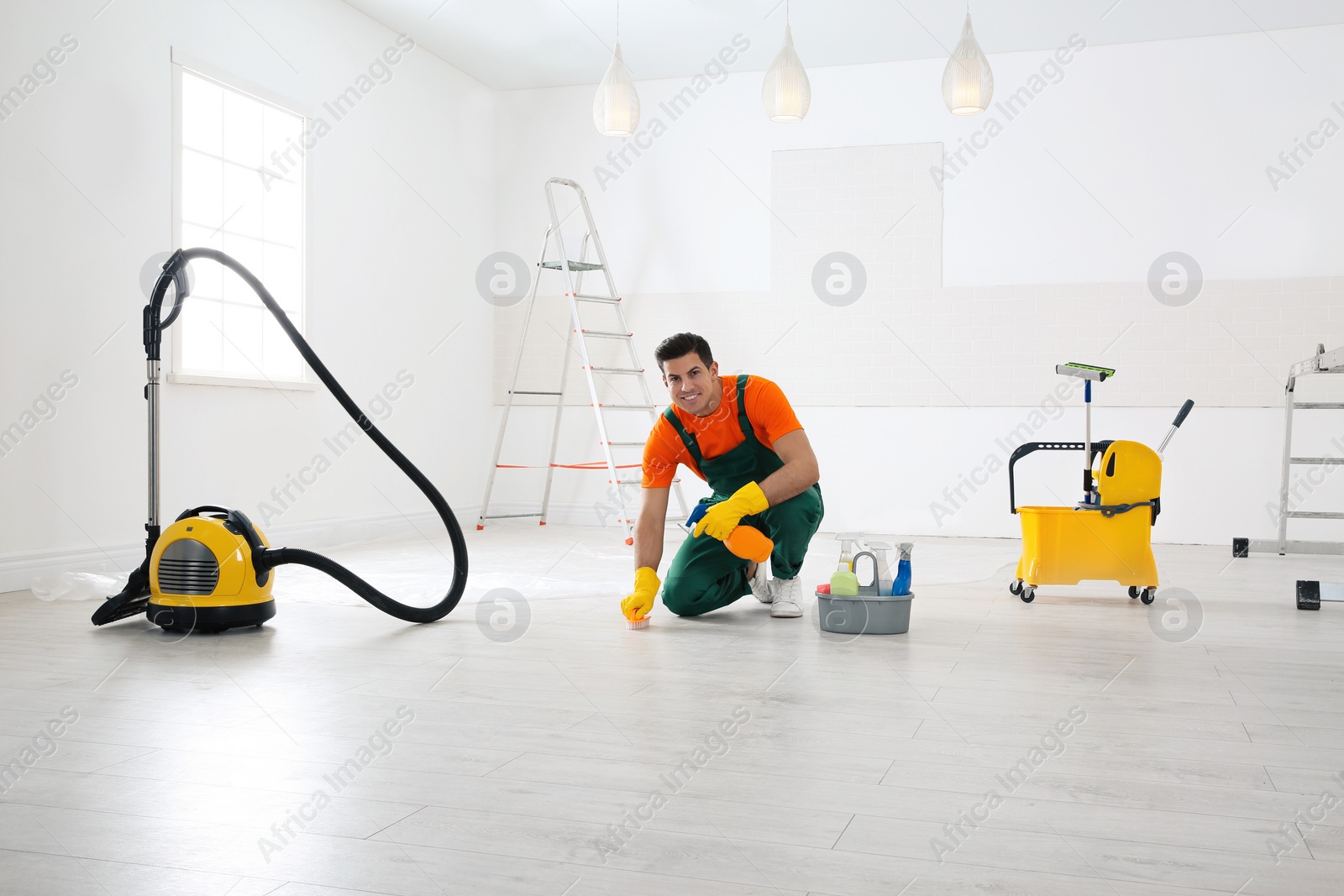 Photo of Professional janitor cleaning floor with brush and detergent after renovation