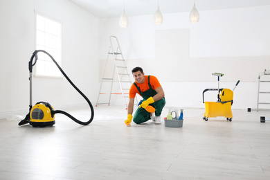 Professional janitor cleaning floor with brush and detergent after renovation