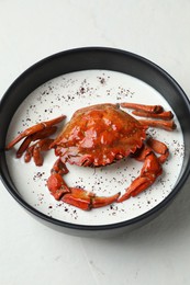 Delicious boiled crab with cream sauce in bowl on white table, above view