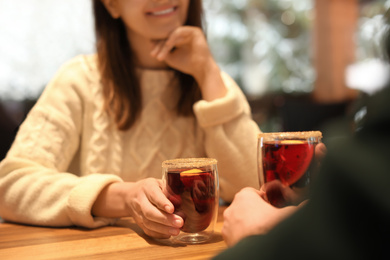 Couple with mulled wine at table in cafe, closeup. Winter vacation