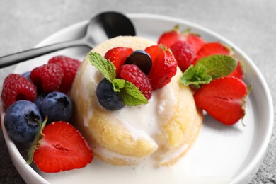 Photo of Delicious vanilla fondant served with fresh berries on grey table, closeup