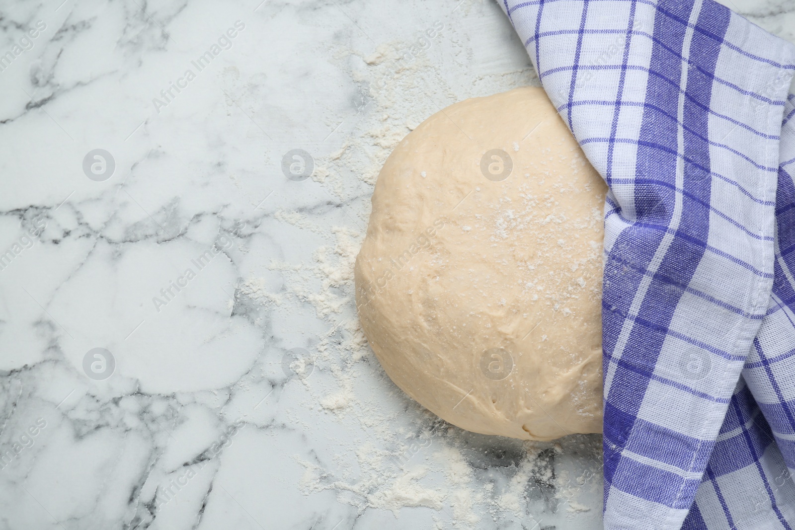 Photo of Fresh yeast dough with flour on white marble table, top view. Space for text