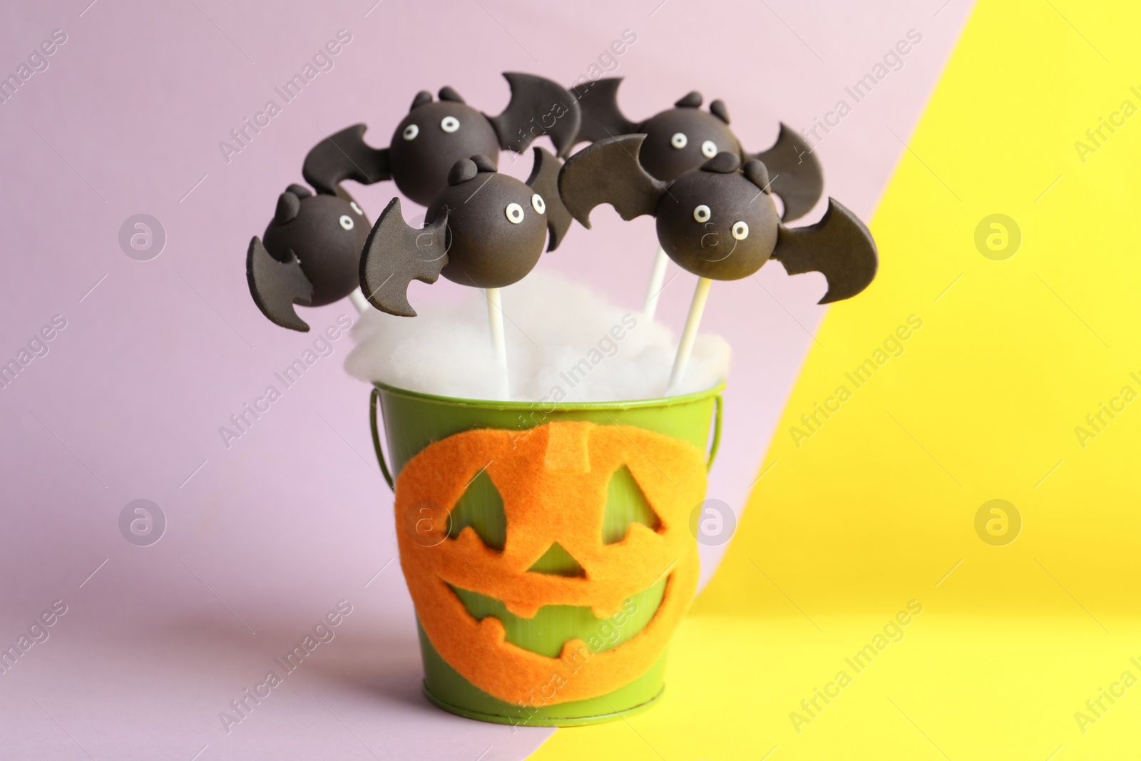 Photo of Delicious bat shaped cake pops on color background. Halloween treat