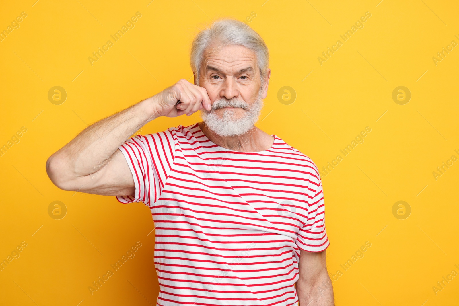 Photo of Senior man touching mustache on orange background