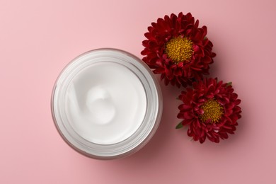 Jar of face cream and chrysanthemum flowers on pink background, flat lay