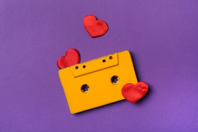 Photo of Music cassette and red hearts on purple background, flat lay. Listening love song
