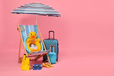 Photo of Deck chair, suitcases and beach accessories on pink background, space for text