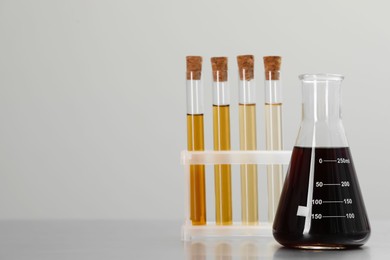 Laboratory glassware with brown liquids on light background. Space for text