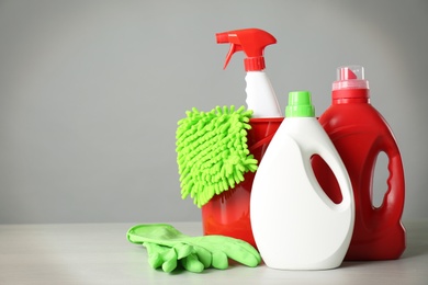 Photo of Bucket and cleaning products on grey table. Space for text