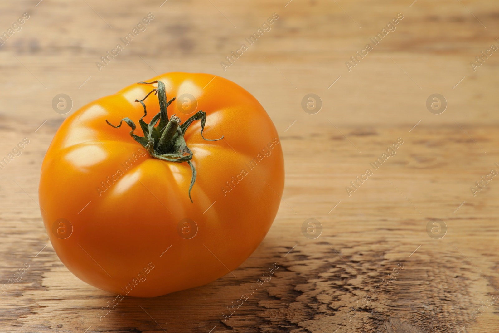 Photo of Fresh ripe yellow tomato on wooden table. Space for text