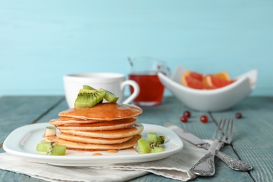 Plate with delicious pancakes on wooden table