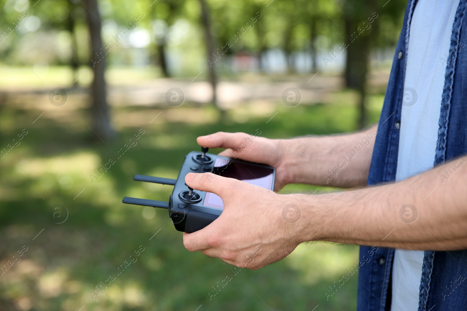 Photo of Man holding new modern drone controller outdoors, closeup of hands