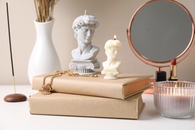 Beautiful David bust candles and books on white dressing table