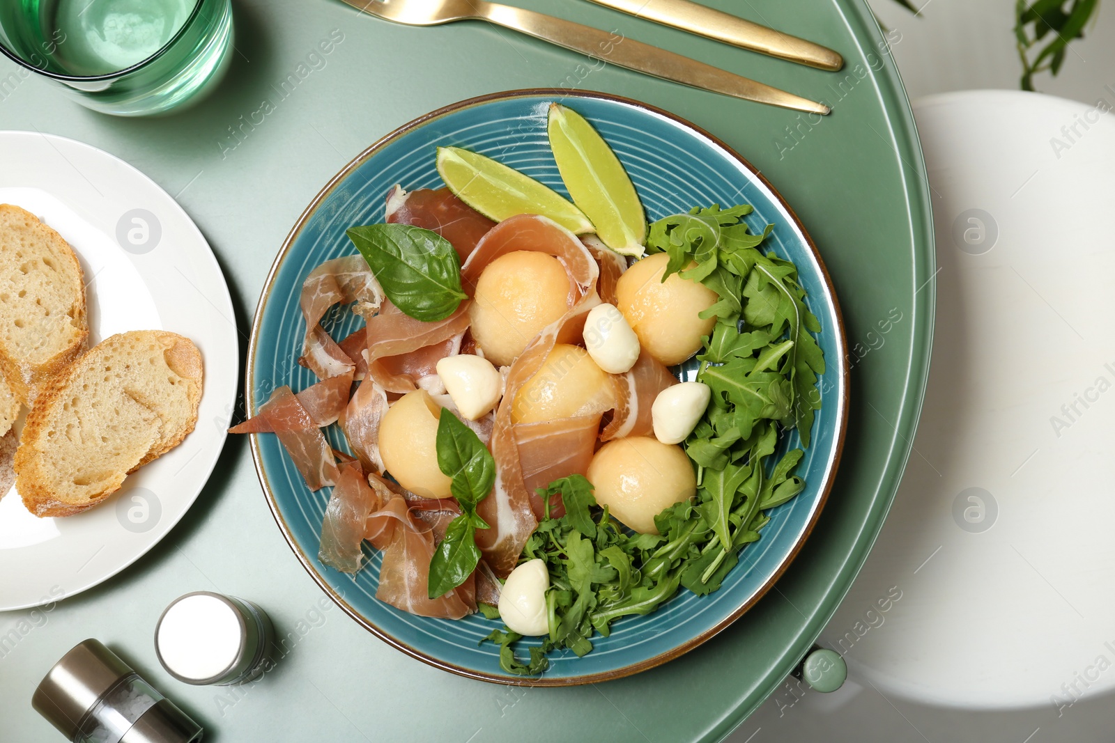 Photo of Flat lay composition with melon and prosciutto appetizer served on table