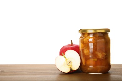 Photo of Tasty apple jam in glass jar and fresh fruits on wooden table against white background, space for text