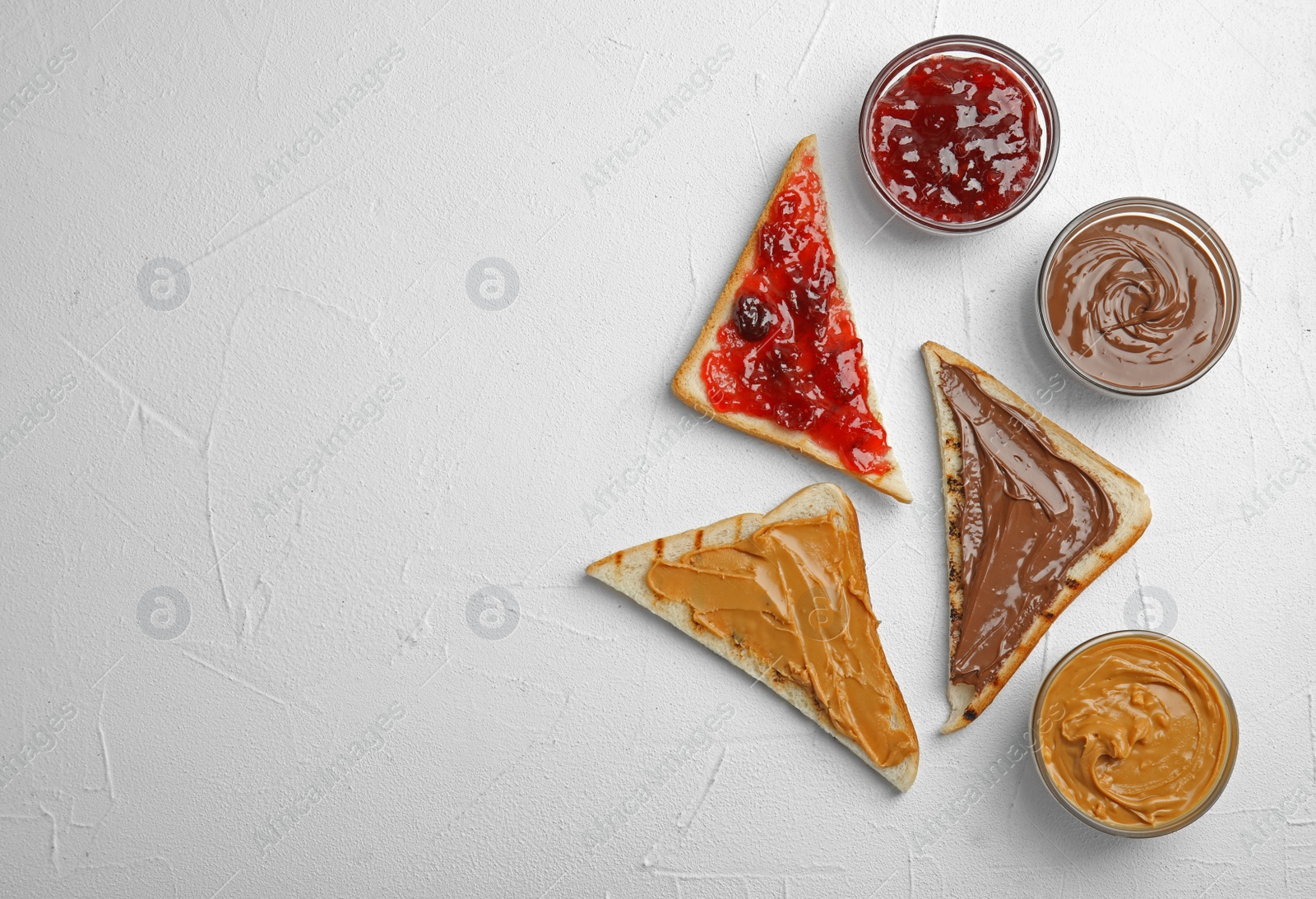 Photo of Slices of bread with different spreads on white table, flat lay. Space for text