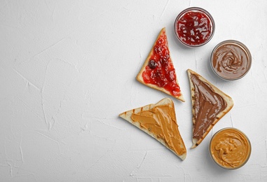 Photo of Slices of bread with different spreads on white table, flat lay. Space for text