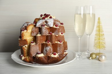 Delicious Pandoro Christmas tree cake with powdered sugar and berries on white wooden table