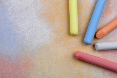 Colorful pastel chalks on abstract drawing, flat lay. Space for text