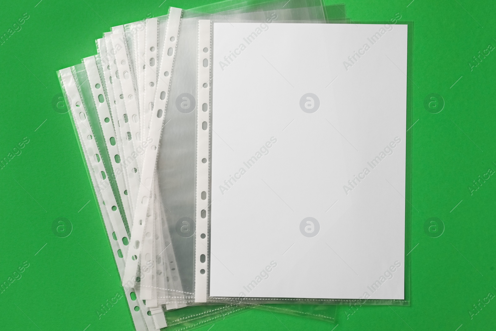 Photo of Punched pockets with paper sheet on green background, flat lay