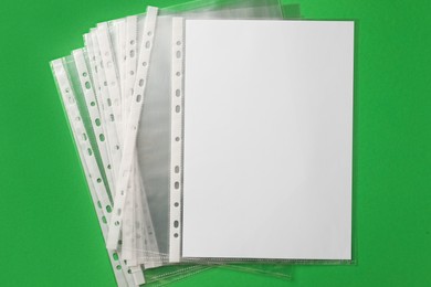 Punched pockets with paper sheet on green background, flat lay