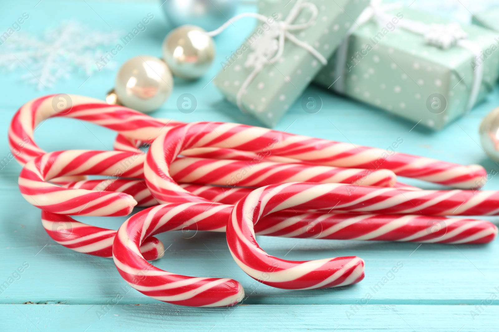 Photo of Many sweet candy canes and Christmas decor on light blue wooden table