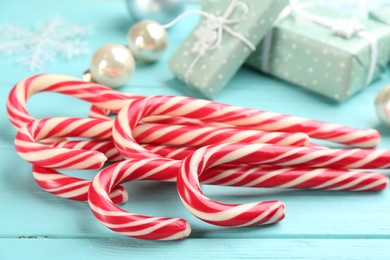 Photo of Many sweet candy canes and Christmas decor on light blue wooden table